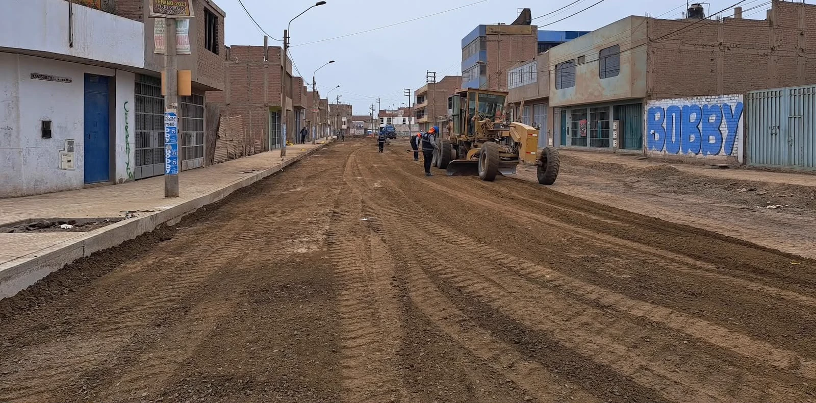 Vía urbana en proceso de nivelación y movimiento de tierras con maquinaria